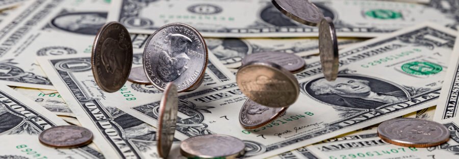 US currency laid out on a table with coins falling on top. Compensation growth slowed slightly in the third quarter of the year, signaling that the white-hot labor market is cooling off.