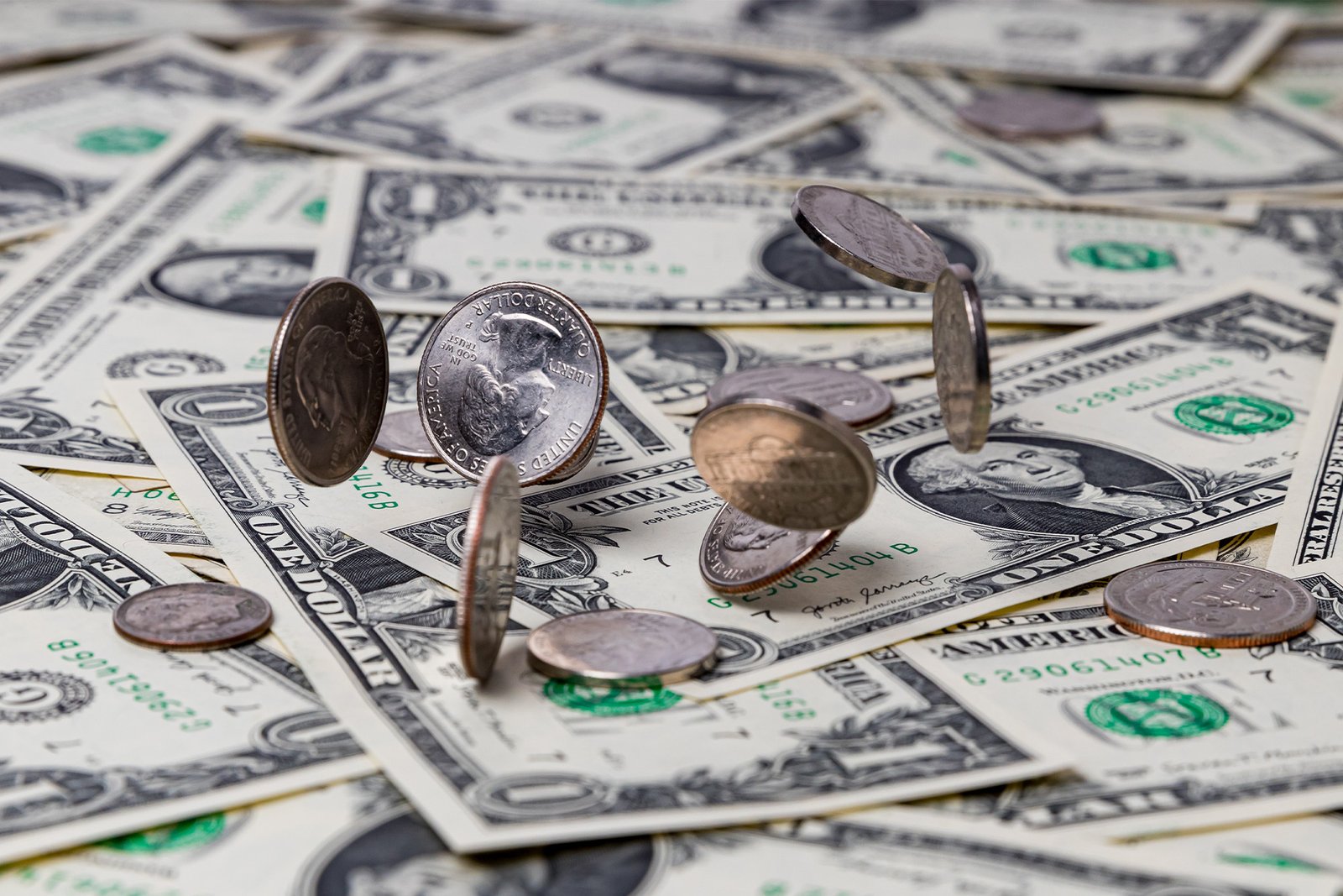 US currency laid out on a table with coins falling on top. Compensation growth slowed slightly in the third quarter of the year, signaling that the white-hot labor market is cooling off.