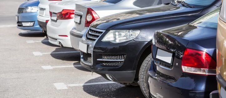Close-up of several cars, parked side-by-side in a large lot, illustrating high-density parking relevant to theft surcharge insurance.