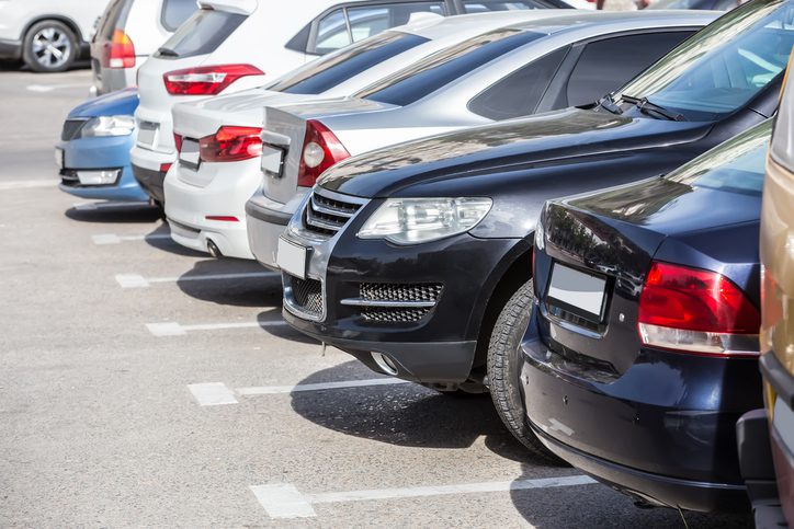 Close-up of several cars, parked side-by-side in a large lot, illustrating high-density parking relevant to theft surcharge insurance.