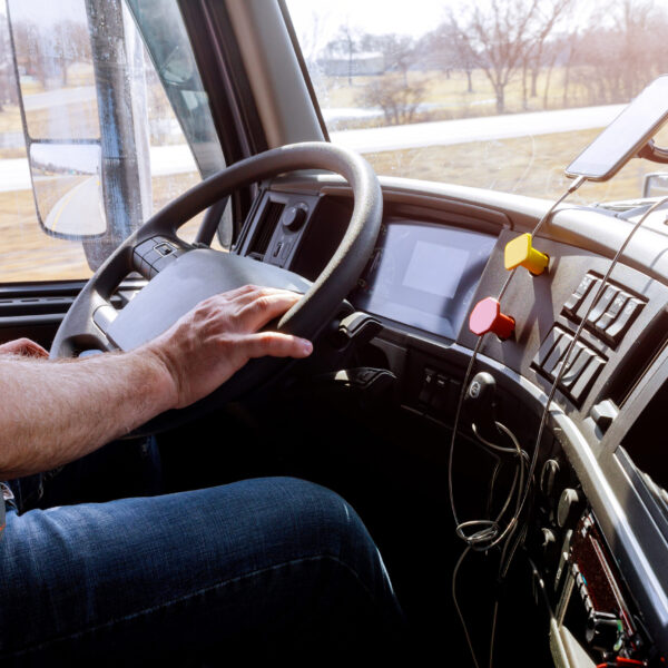 Driver in cabin of big modern truck vehicle on highway