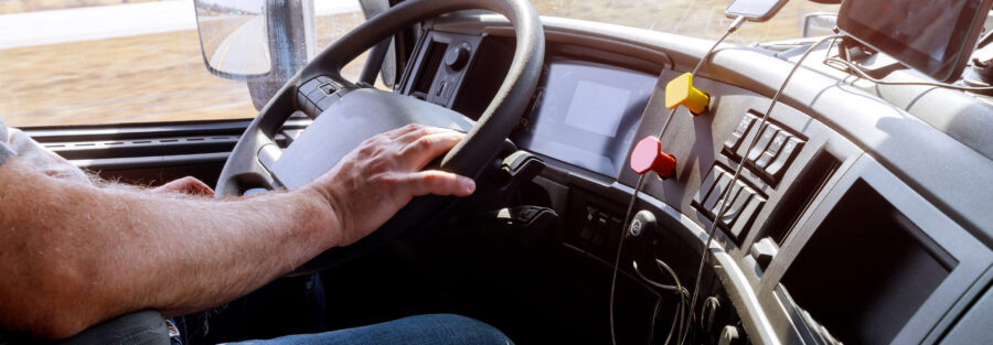 Driver in cabin of big modern truck vehicle on highway
