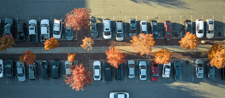 Cars parked in an outdoor lot surrounded by fall foliage.