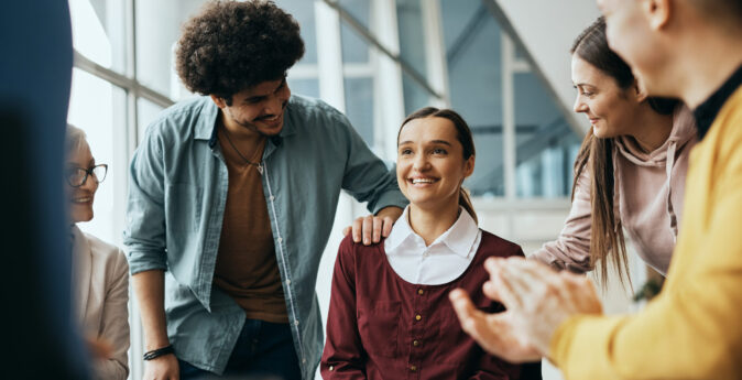 Young happy woman receives support from attenders of group therapy at mental health center.