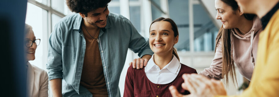 Young happy woman receives support from attenders of group therapy at mental health center.